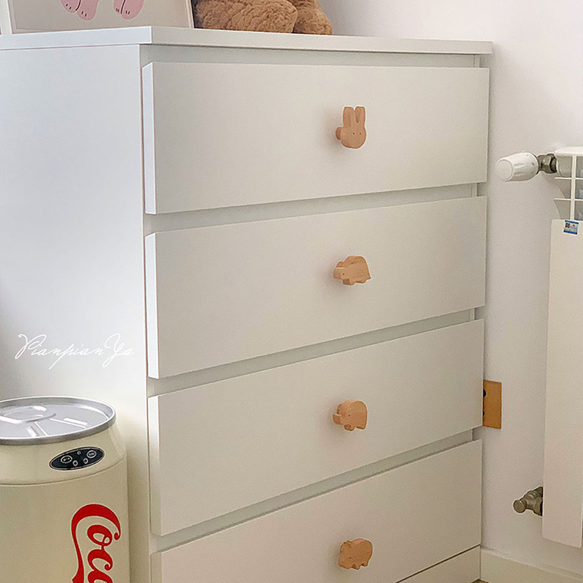 Turtle-shaped wood knobs on white chest drawers.