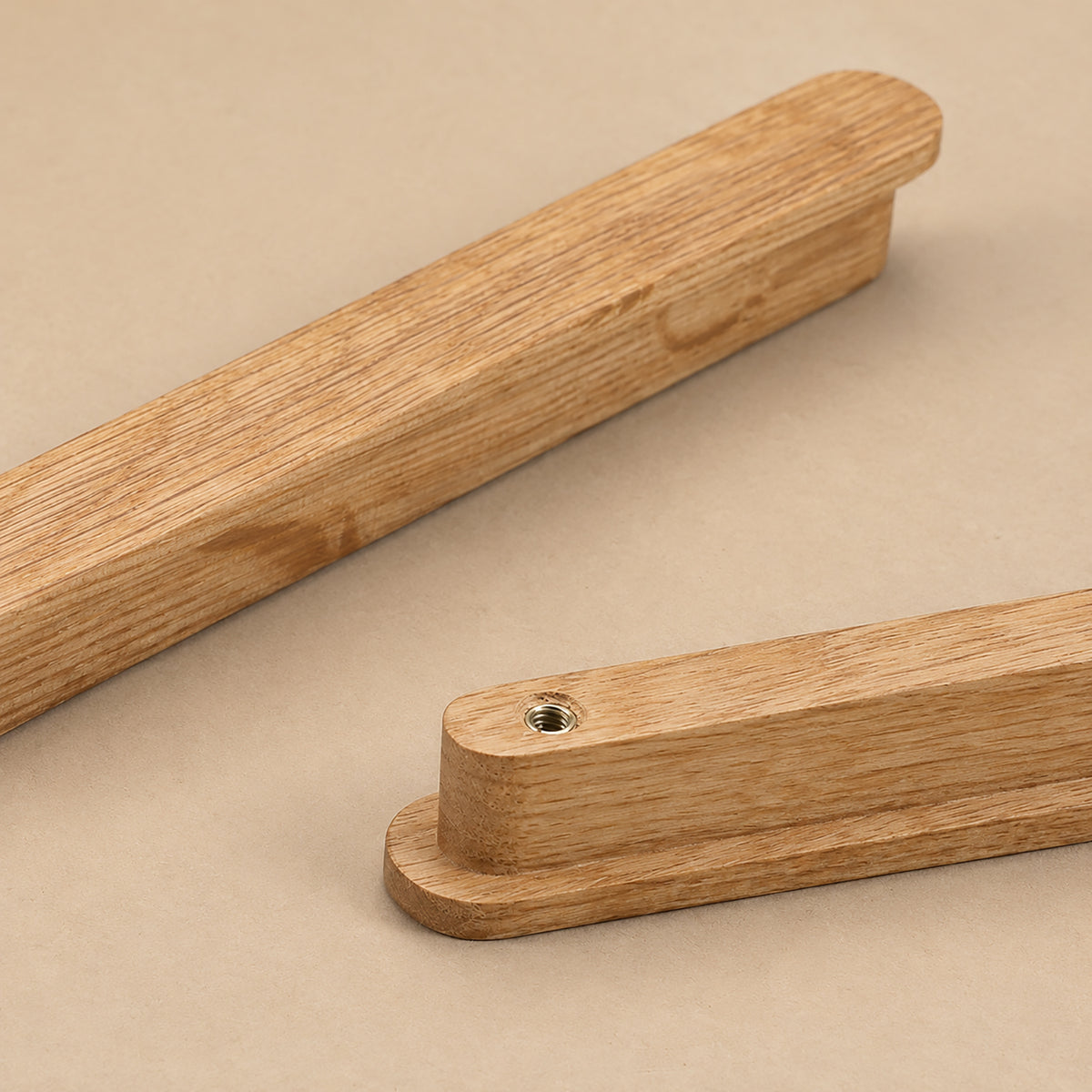 Close-up of oak wood cabinet finger pull profile and mounting hole.