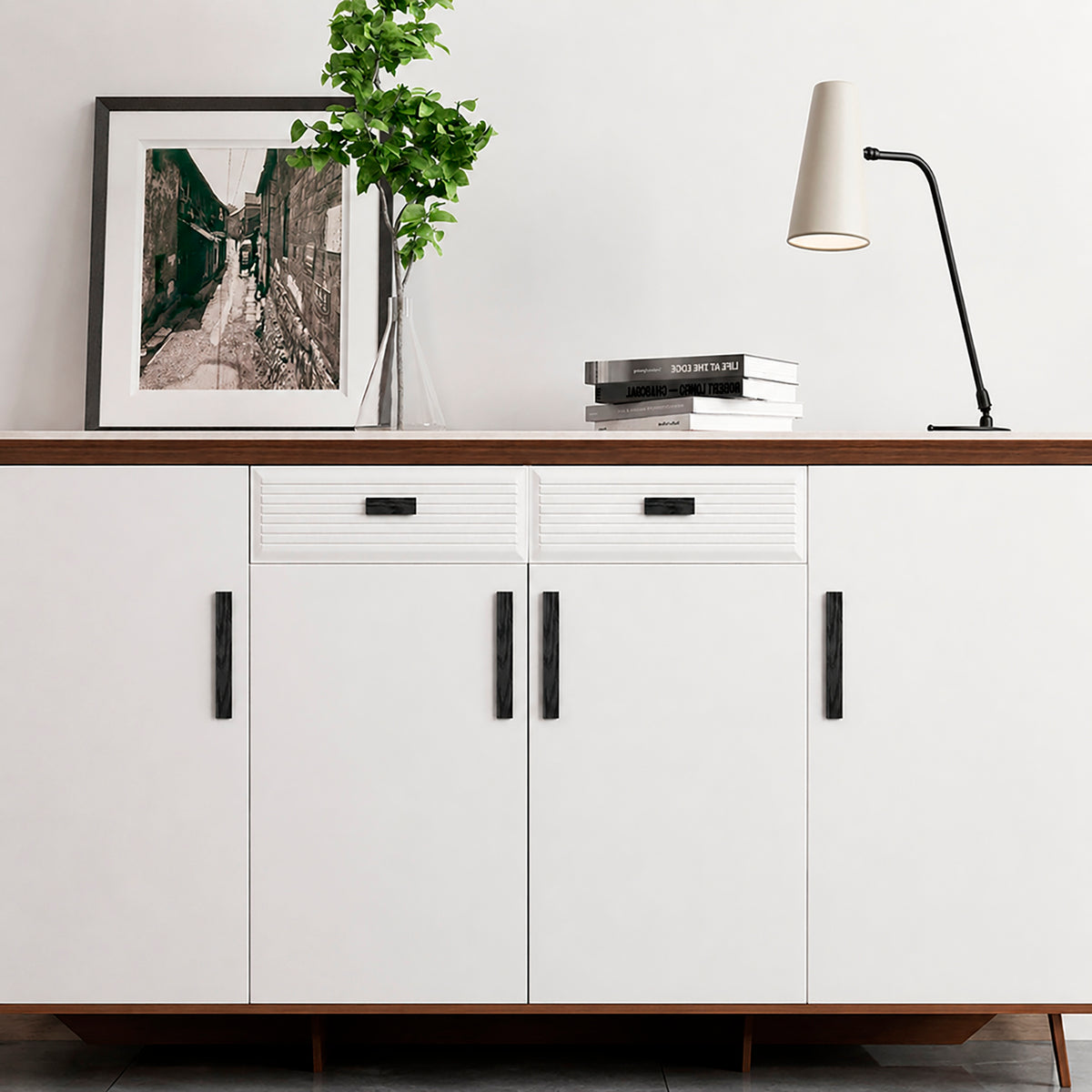 Black wood finger pulls fitted to the doors and drawers of a white sideboard.