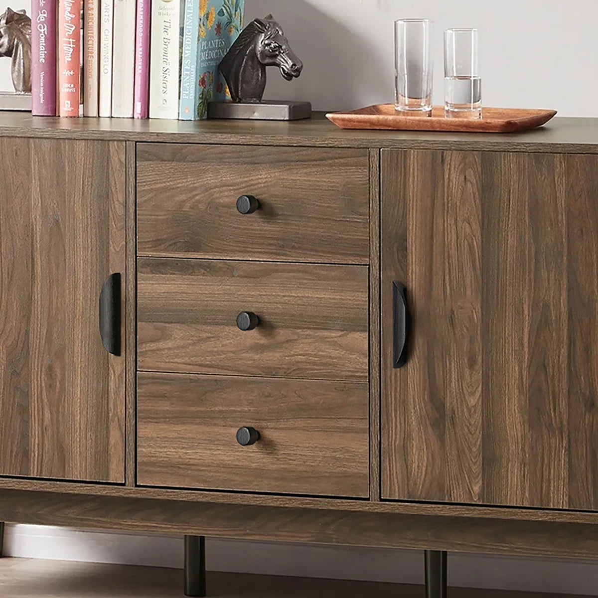 Black wood finger pulls and round knobs fitted to a walnut sideboard.