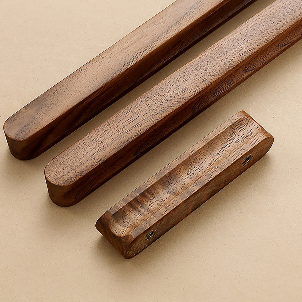 Two walnut wood finger pulls showing the front grip and rear mounting holes.