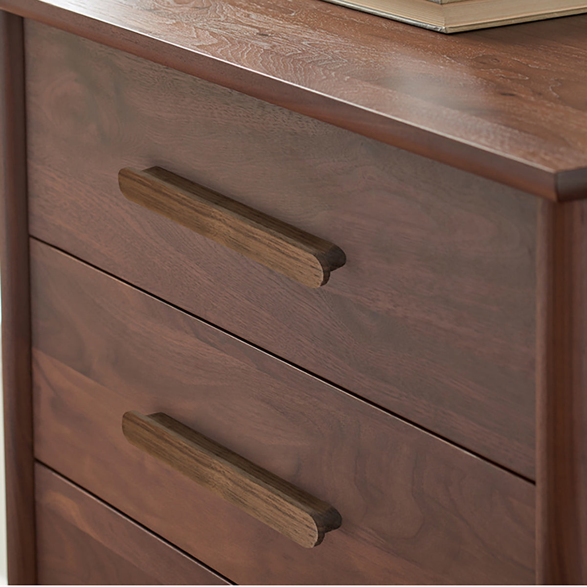 Walnut wood slim cabinet finger pull installed on cabinetry.