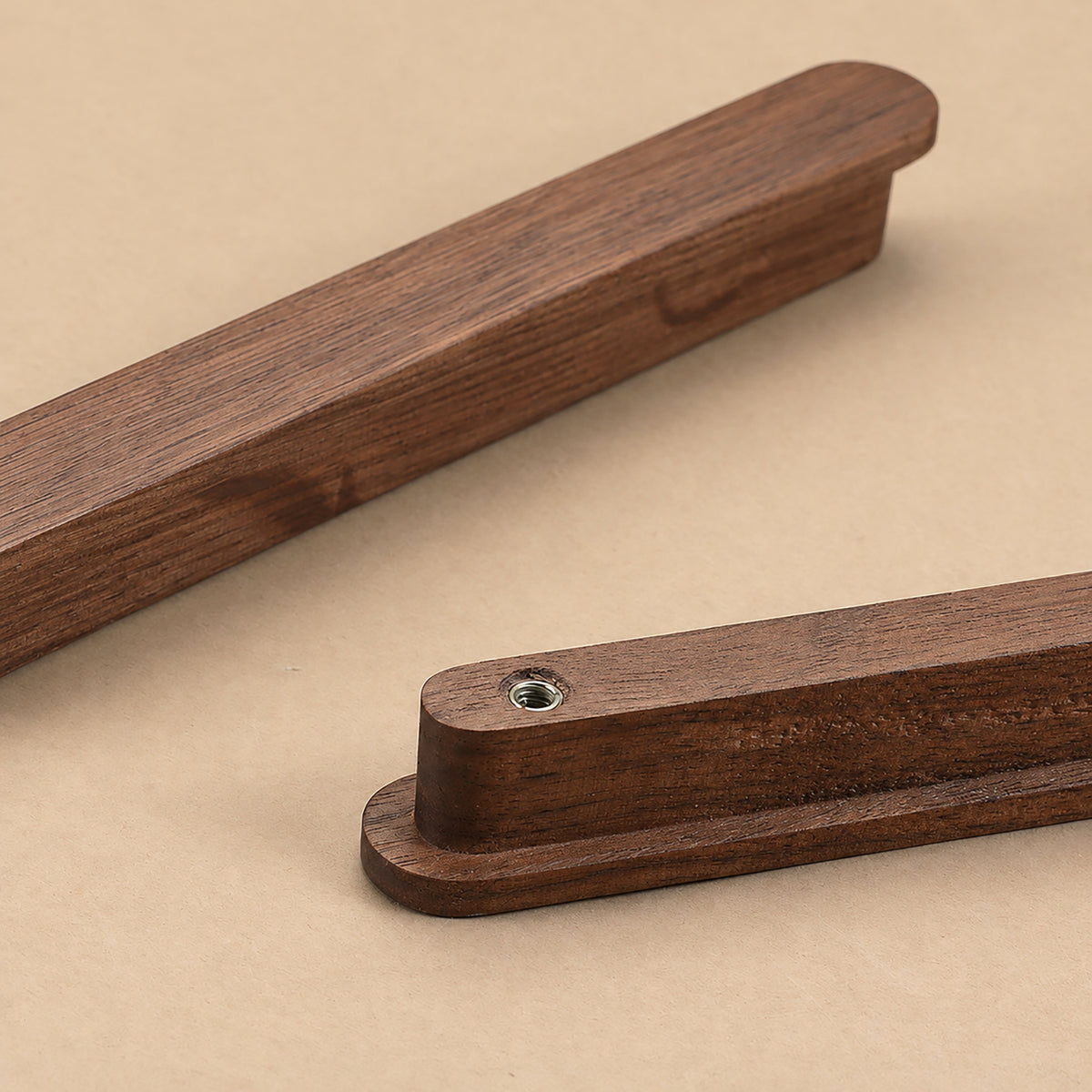Close-up of walnut wood cabinet finger pull profile and mounting hole.