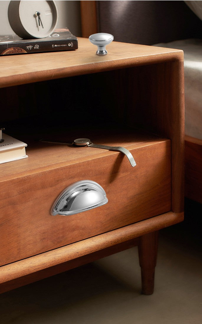 Solid brass open-back cup pull in Polished Chrome shown on the drawer of a bedside table.