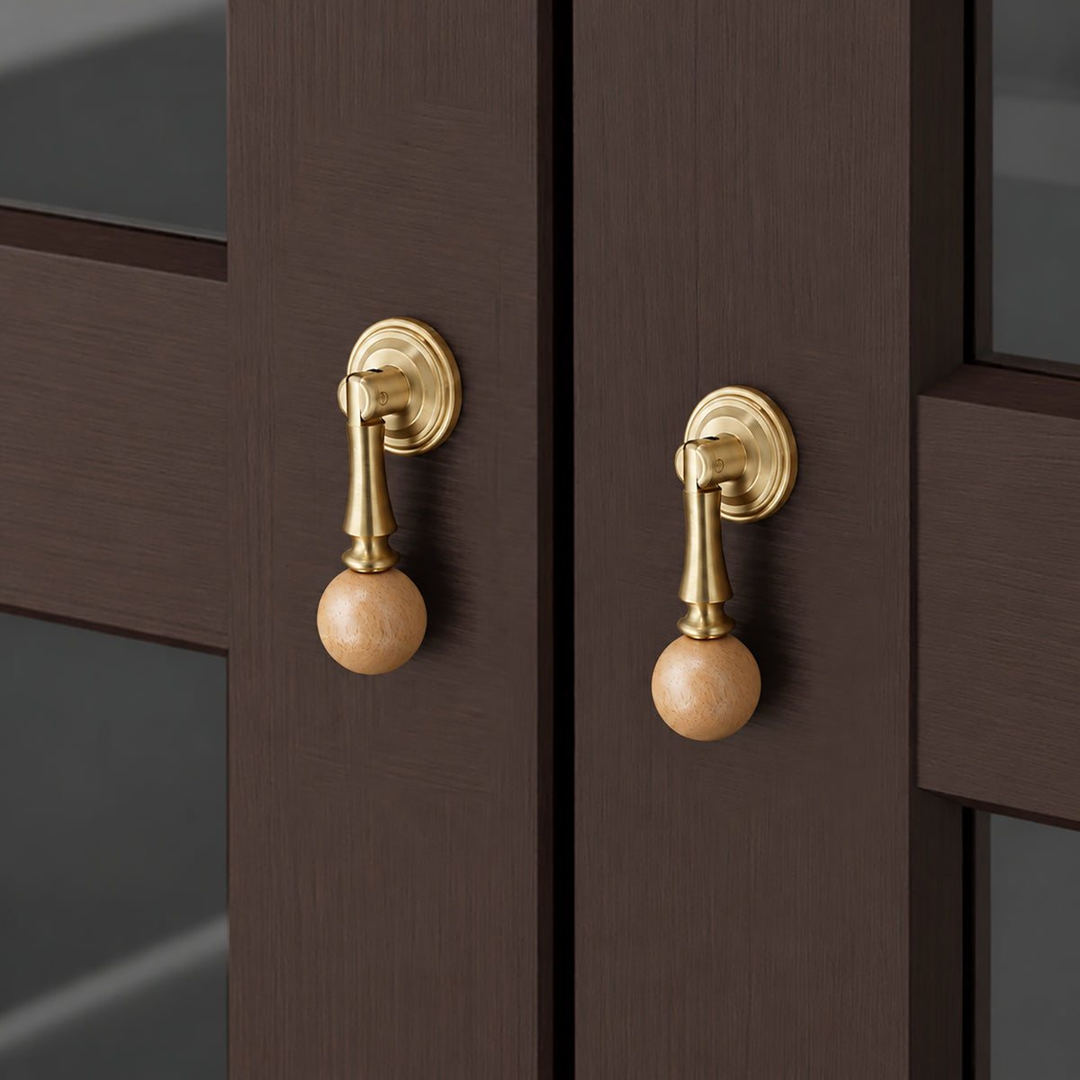 In-use view of light wood ball drop pull with a brass stem and round base, style #5.