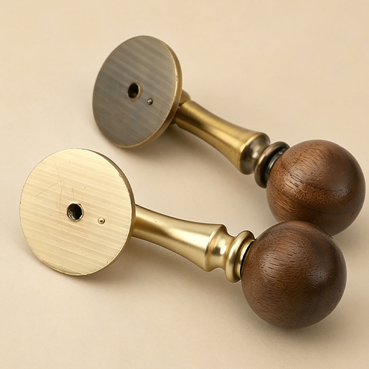 Two brass drop pulls with dark wood ball ends, showing rear mounting holes.