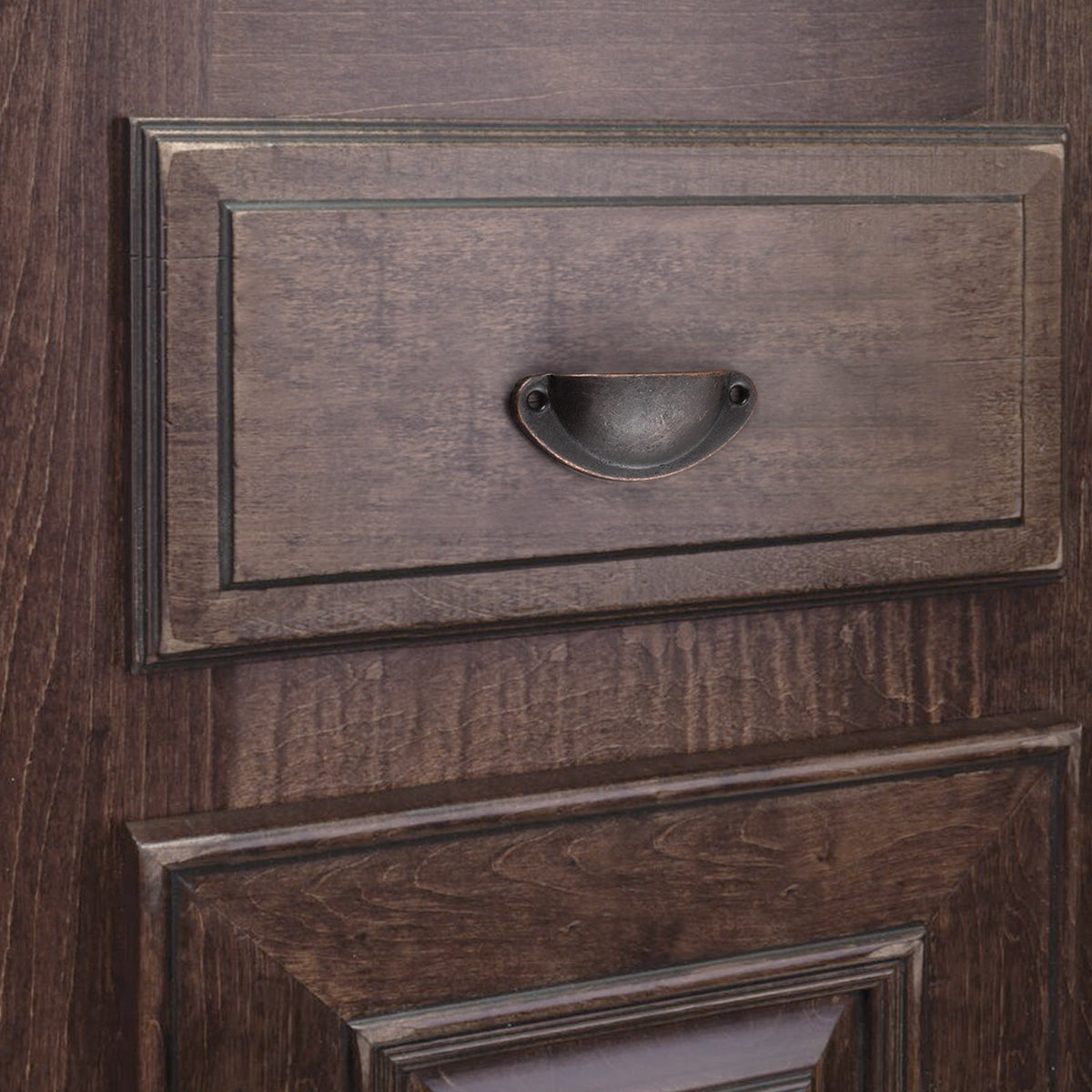 Raised-rim half-moon iron cup pull in Antique Copper on a dark wood-grain drawer.