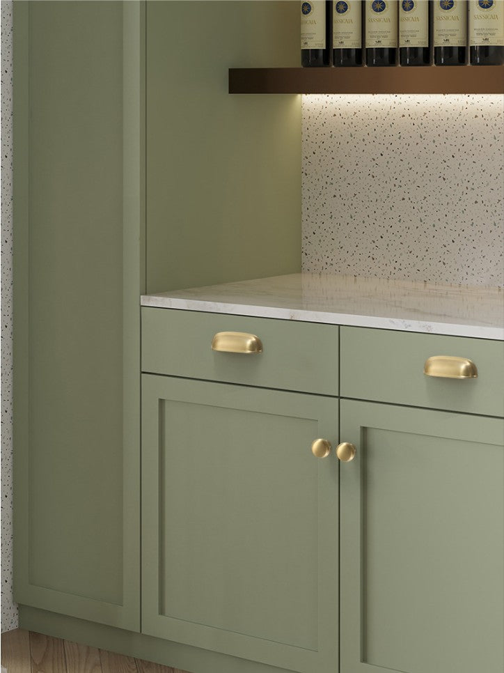 Solid brass rounded dome cup pulls in Satin Brass on green cabinet drawers.