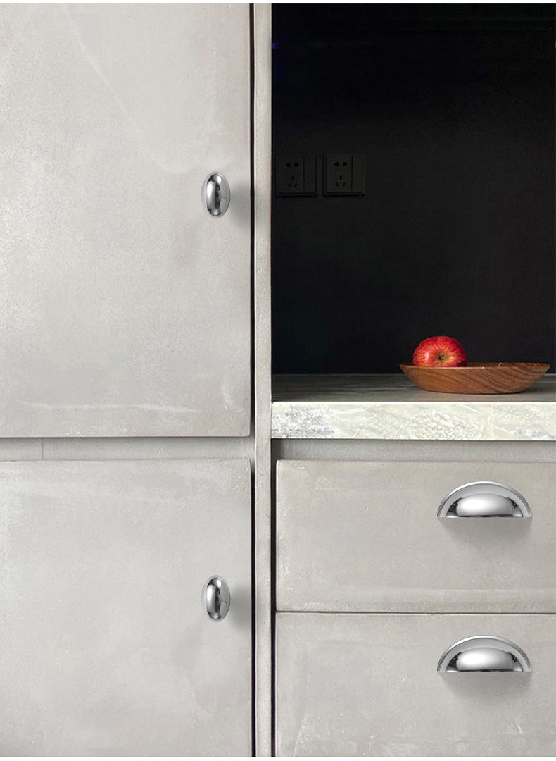 Solid brass smooth half-moon cup pulls in Polished Chrome on light-colored kitchen drawers.