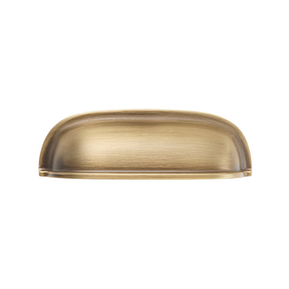Solid brass rounded dome cup pull in Aged Brass finish on a white background.