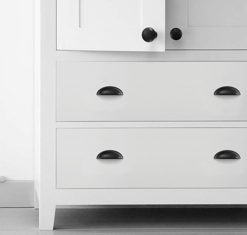 Four matte black half-moon cup pulls on two white dresser drawers.